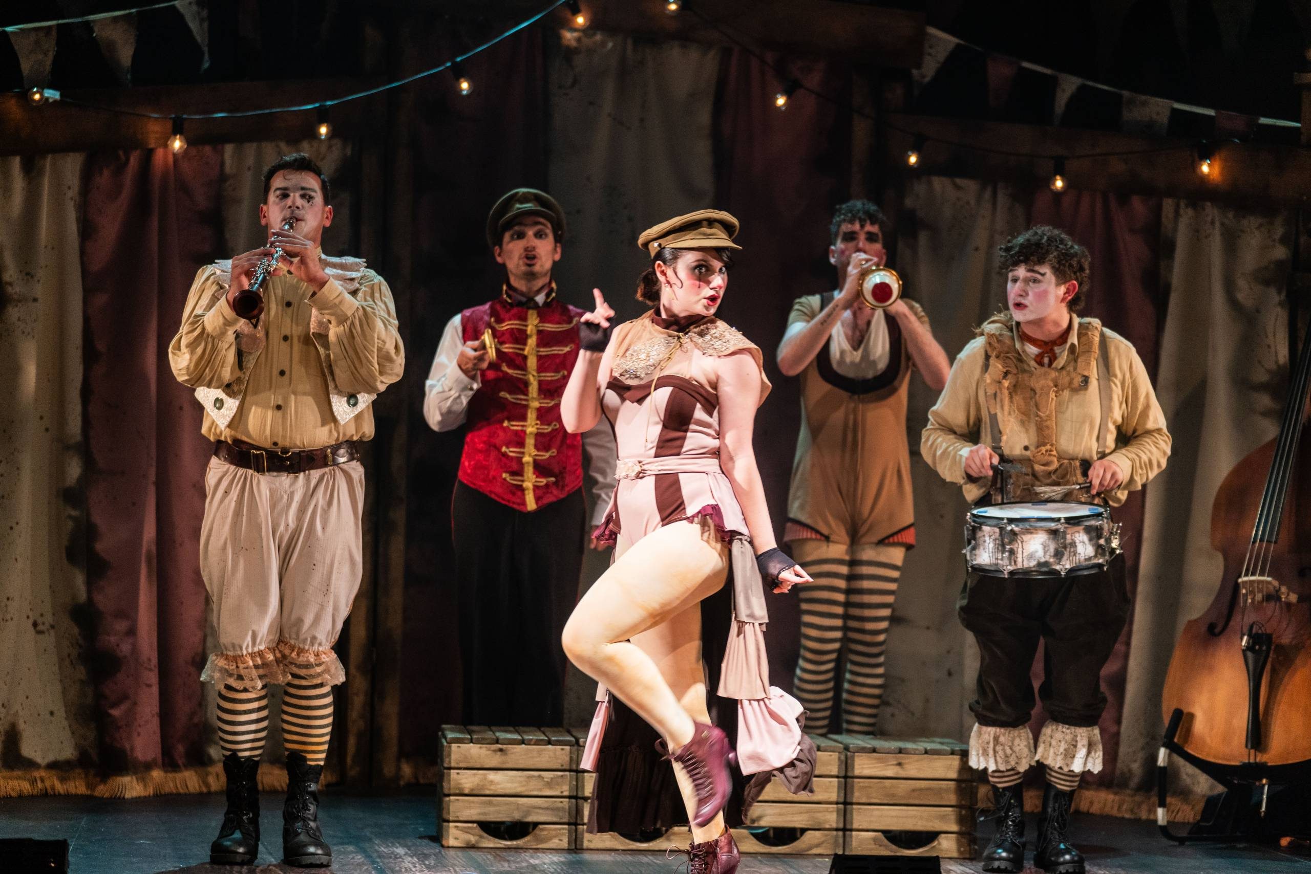 Oh What A Lovely War Four male characters dressed as clown style soldiers play instruments while a female character dances.