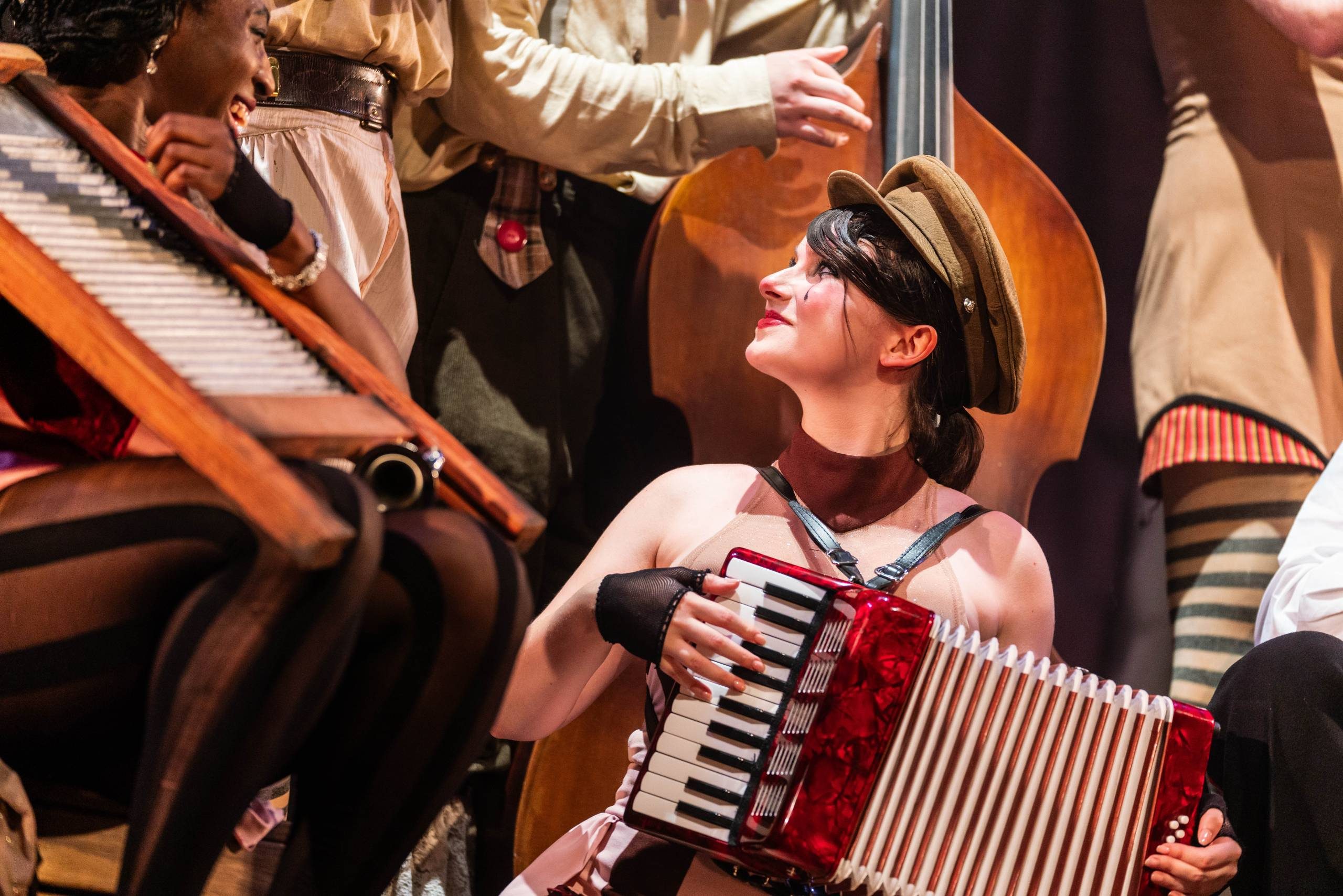 Oh What A Lovely War A female character wearing face makeup, and a soldiers hat plays an accordion.