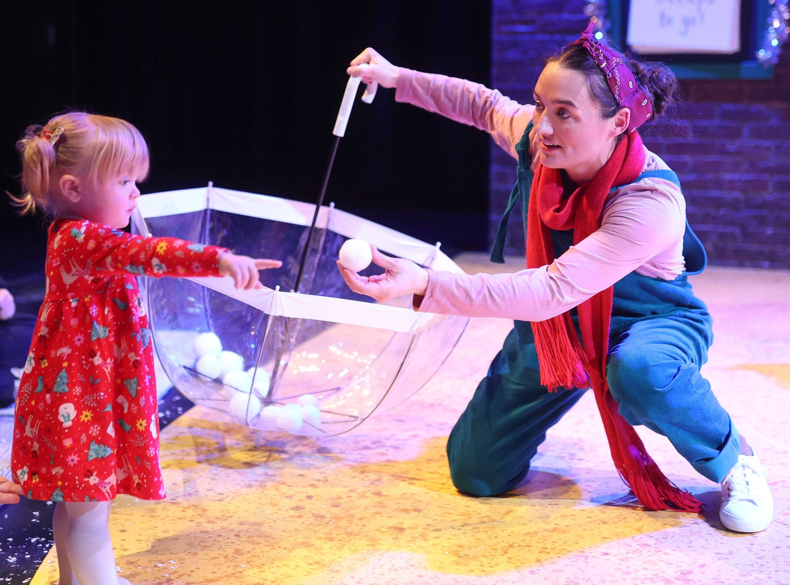 Counting Down to Christmas Female character holding an umbrellas passes a snowball to a young child.