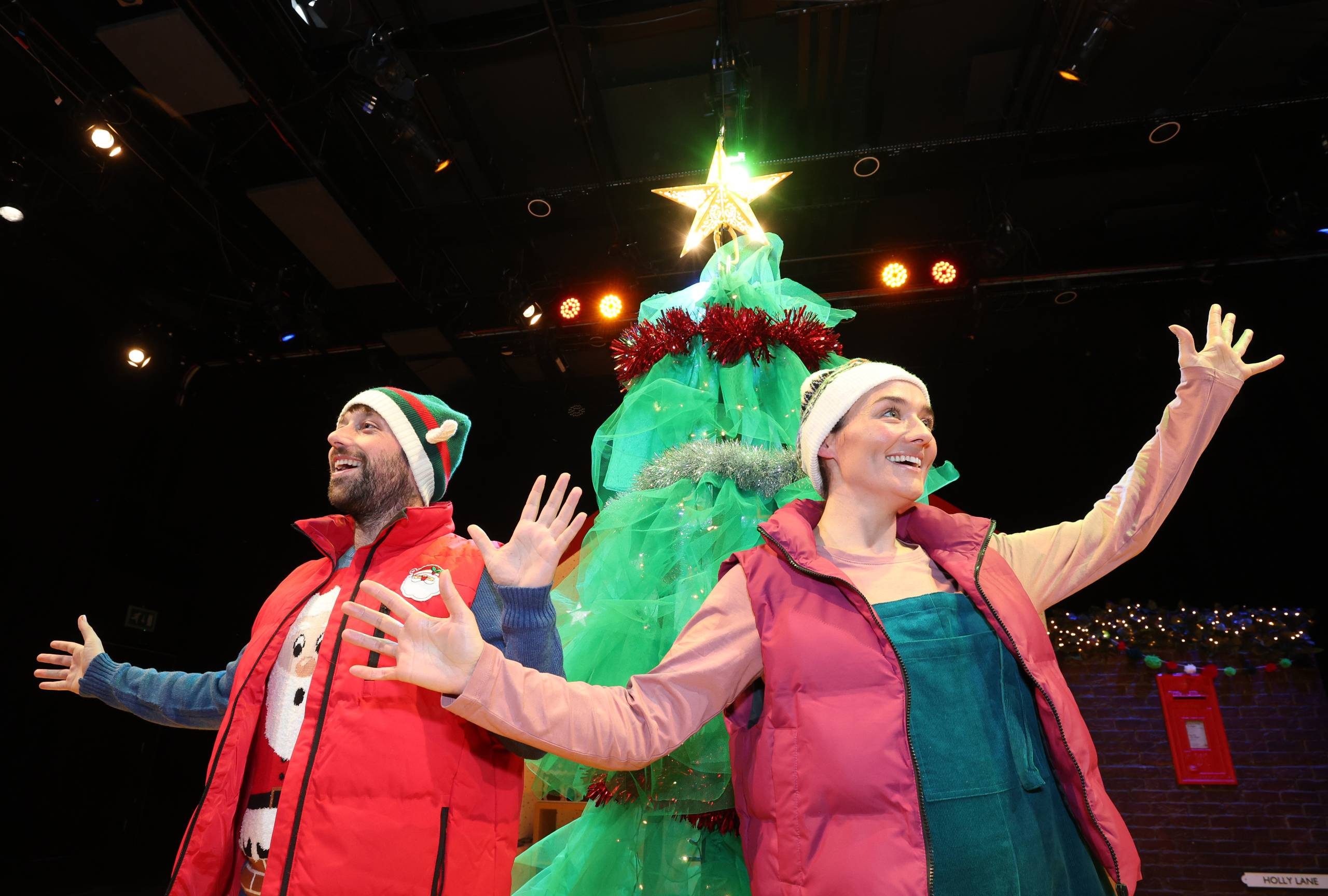 Counting Down to Christmas Male and female character stand in front of a tall Christmas tree with a glowing star on top