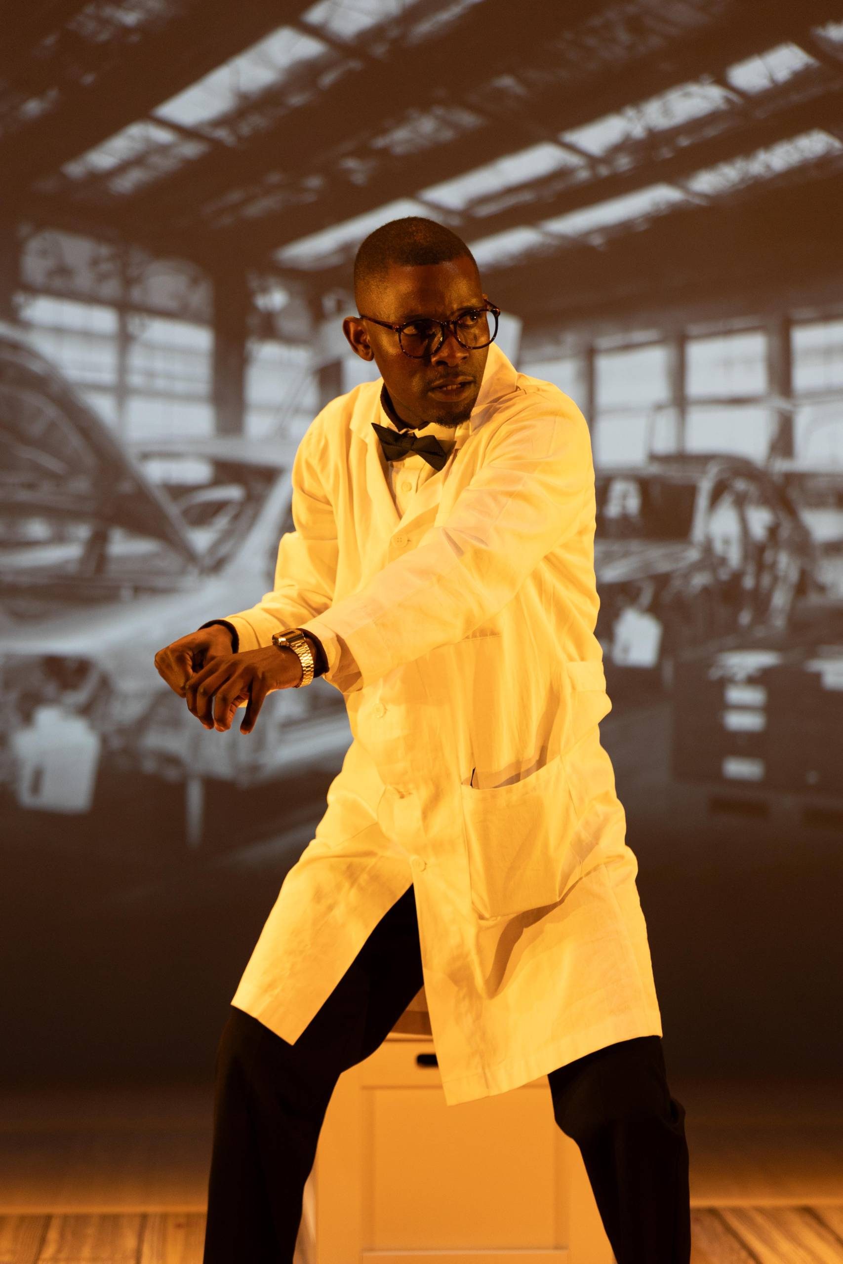 Sizwe Banzi Is Dead One male character wearing a lab coat and bow tie