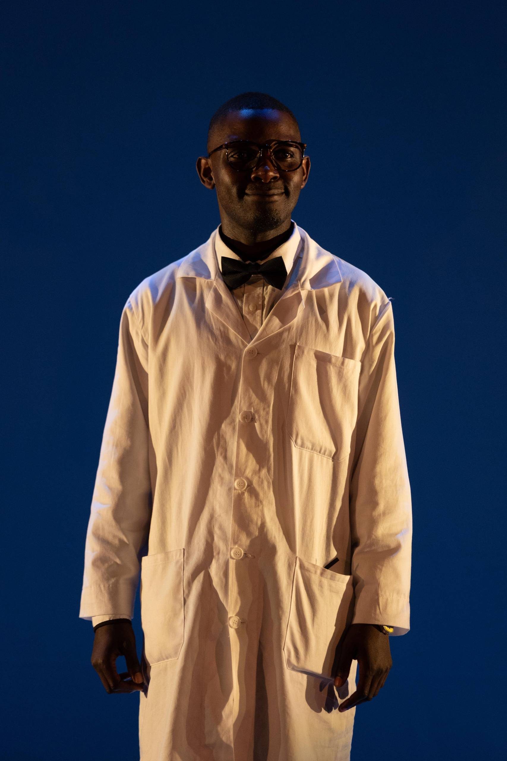 Sizwe Banzi Is Dead One male character wearing a lab coat and bow tie.